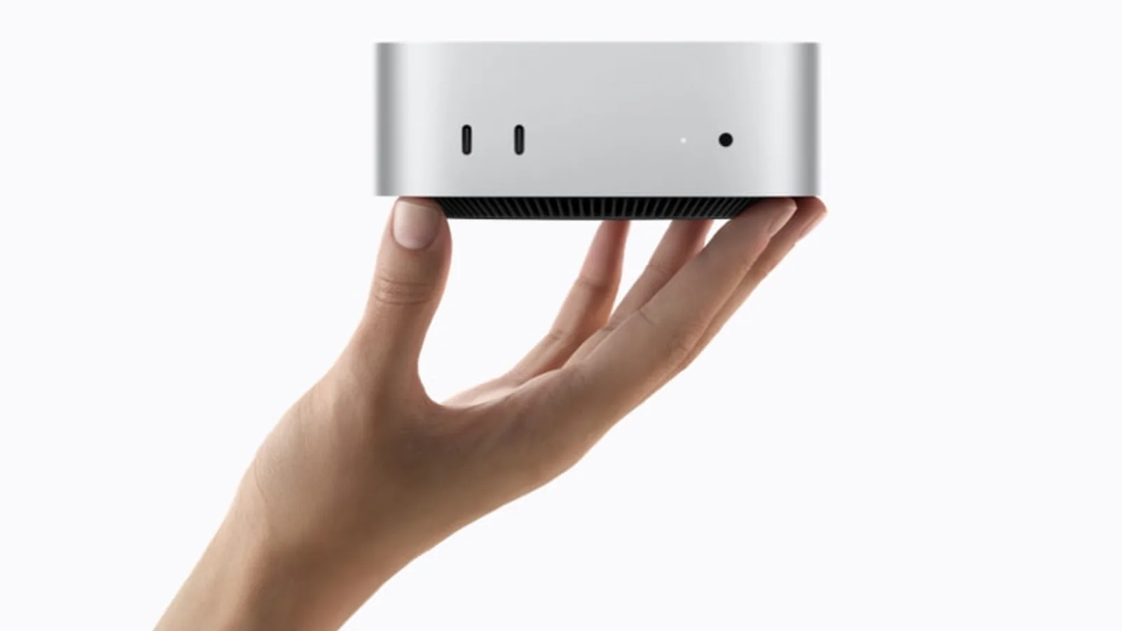 Photo officielle du Mac mini M6 tenu dans une main sur fond blanc
