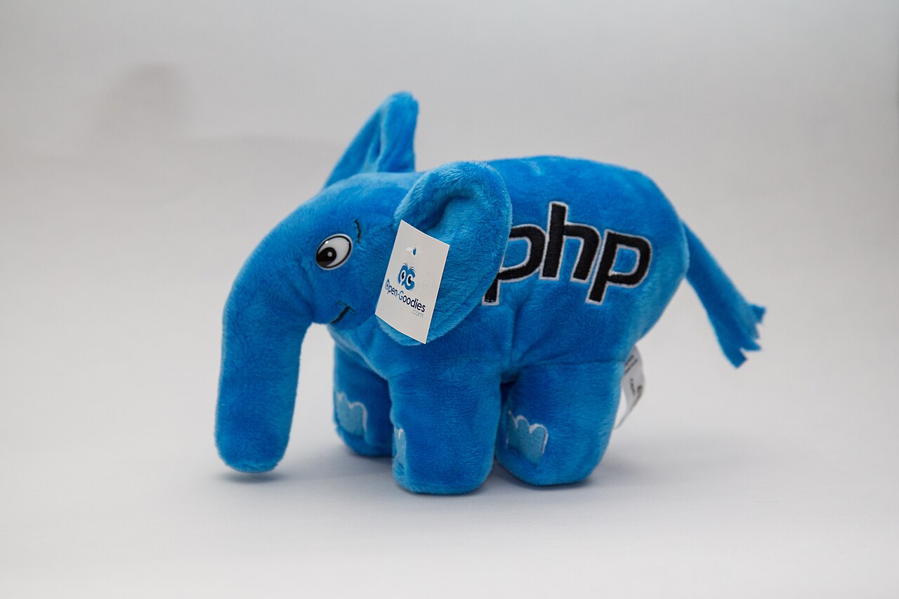 Peluche bleue ElePHPant portant le logo PHP, photographiée sur un fond clair.