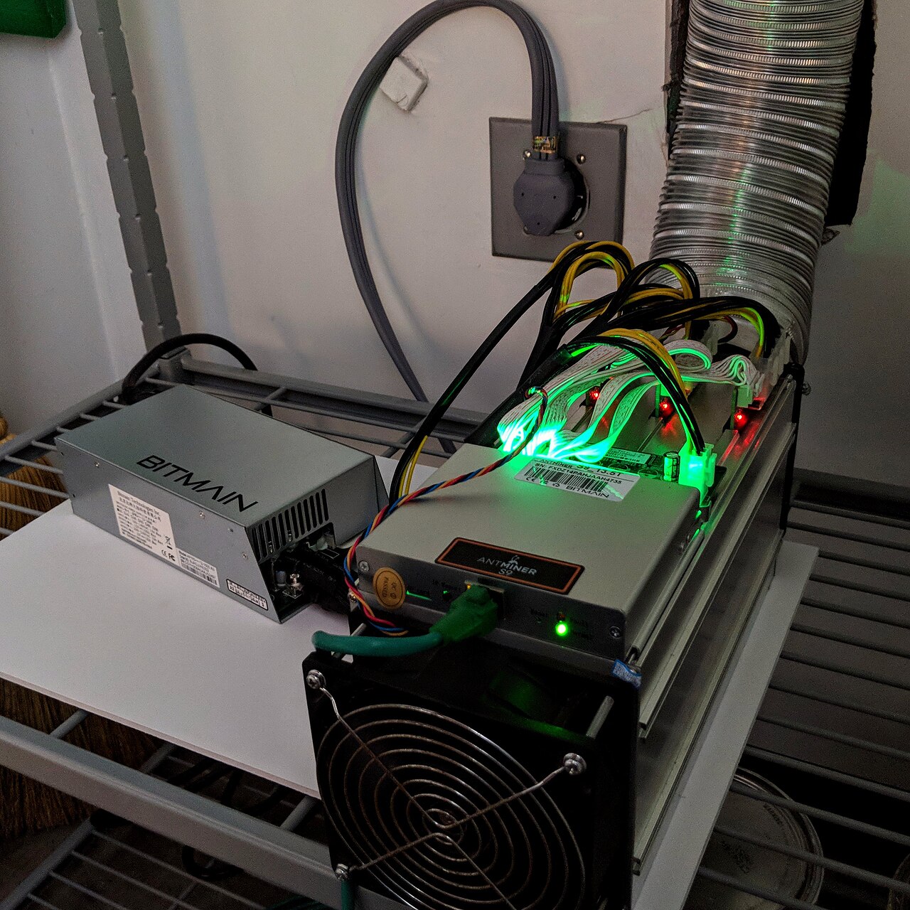Appareil Antminer S9, ventilateur et alimentation posés sur une étagère