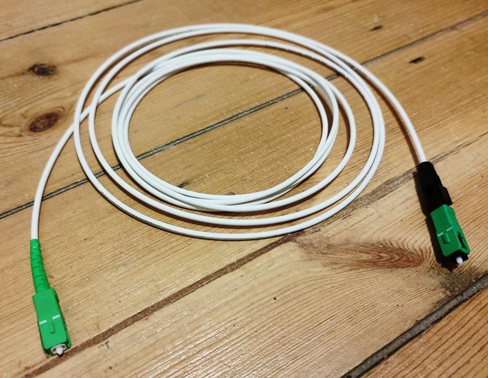 Câble de fibre optique blanc avec deux connecteurs verts SC-APC, photo d’illustration.
