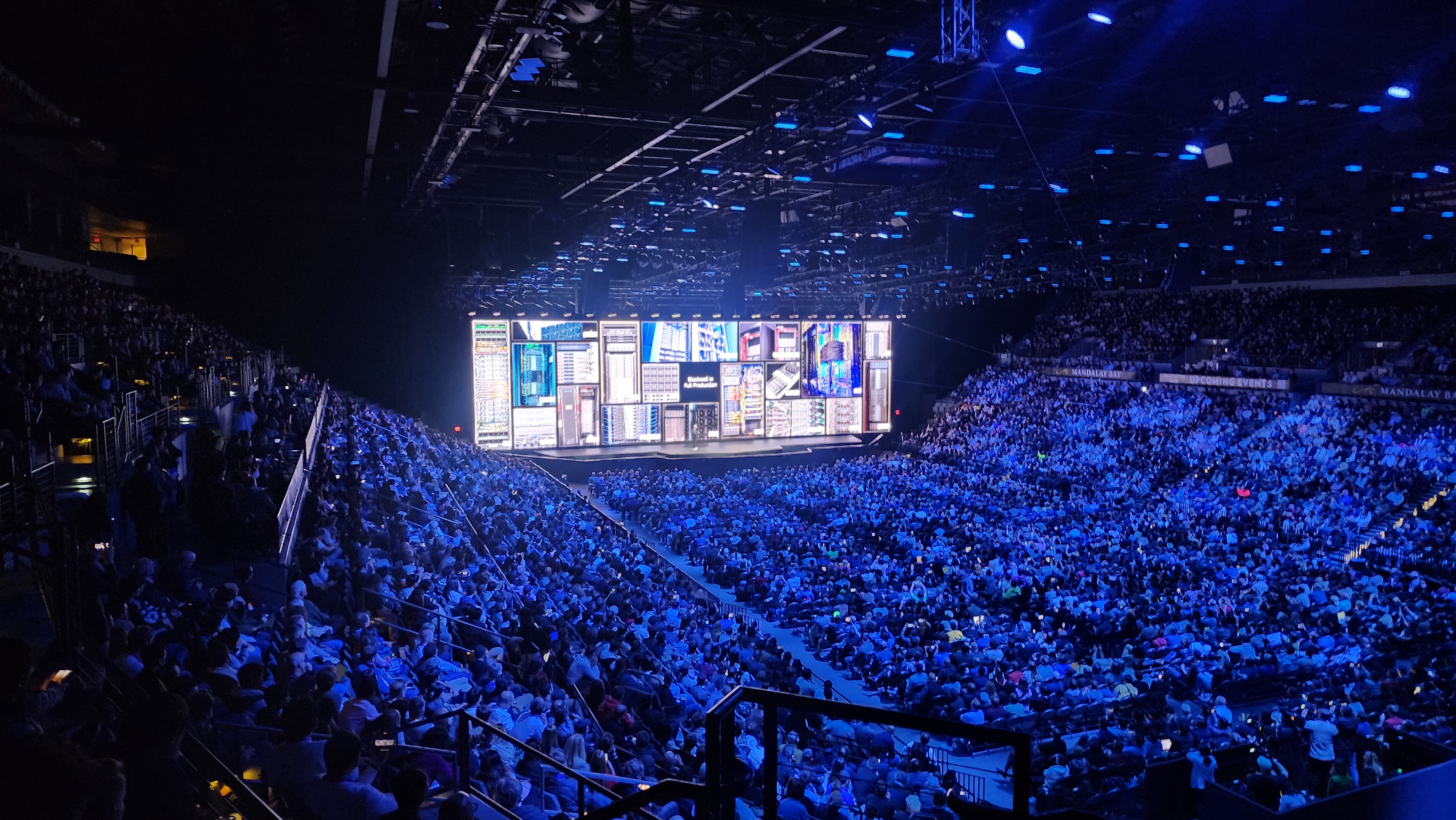 Vue d’ensemble de la conférence NVIDIA au CES 2025 à Las Vegas : public dans une salle éclairée en bleu et scène présentant des équipements informatiques.