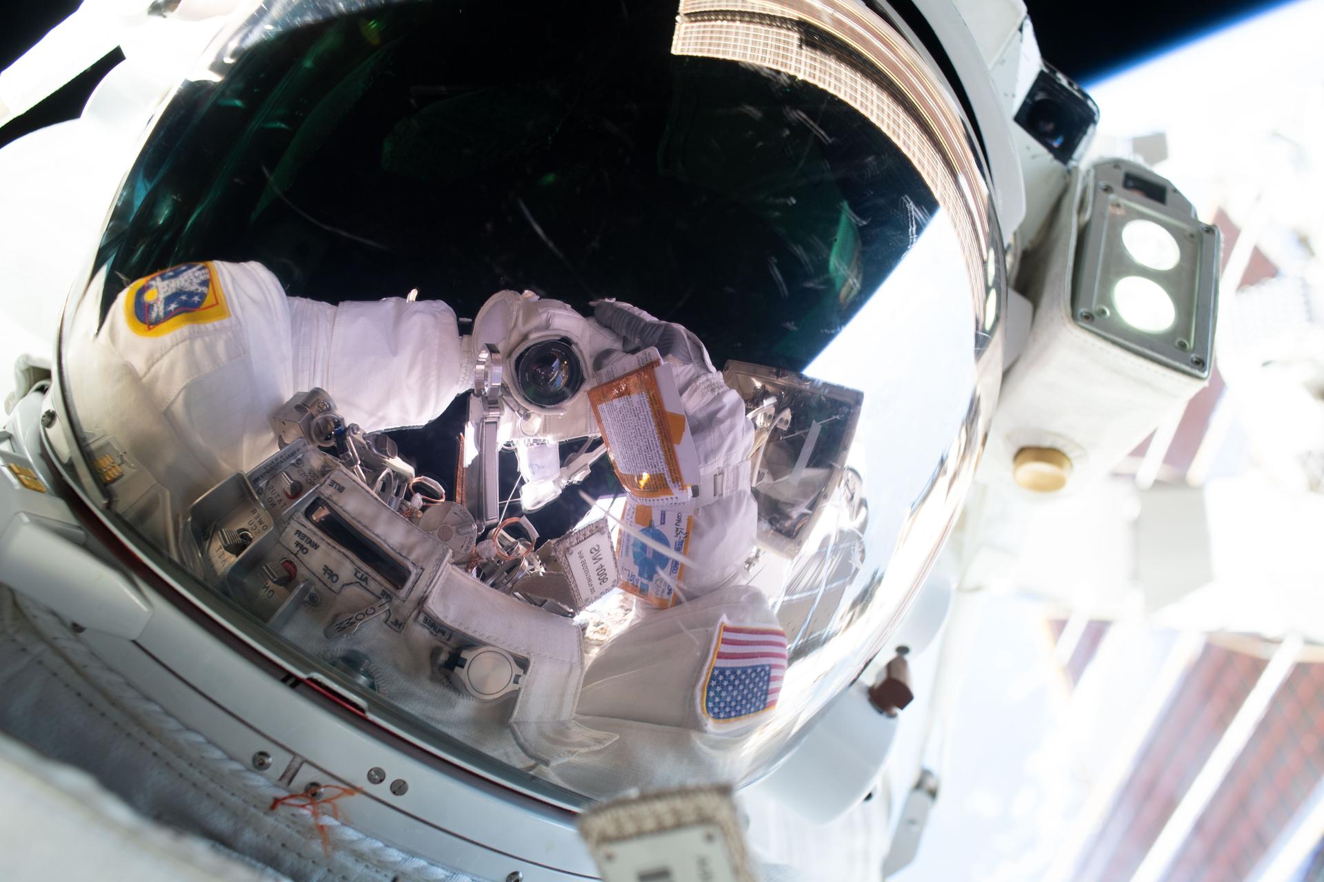 Reflet d’Anil Menon et de son appareil photo dans la visière de son scaphandre, lors d’une sortie spatiale en août 2026.
