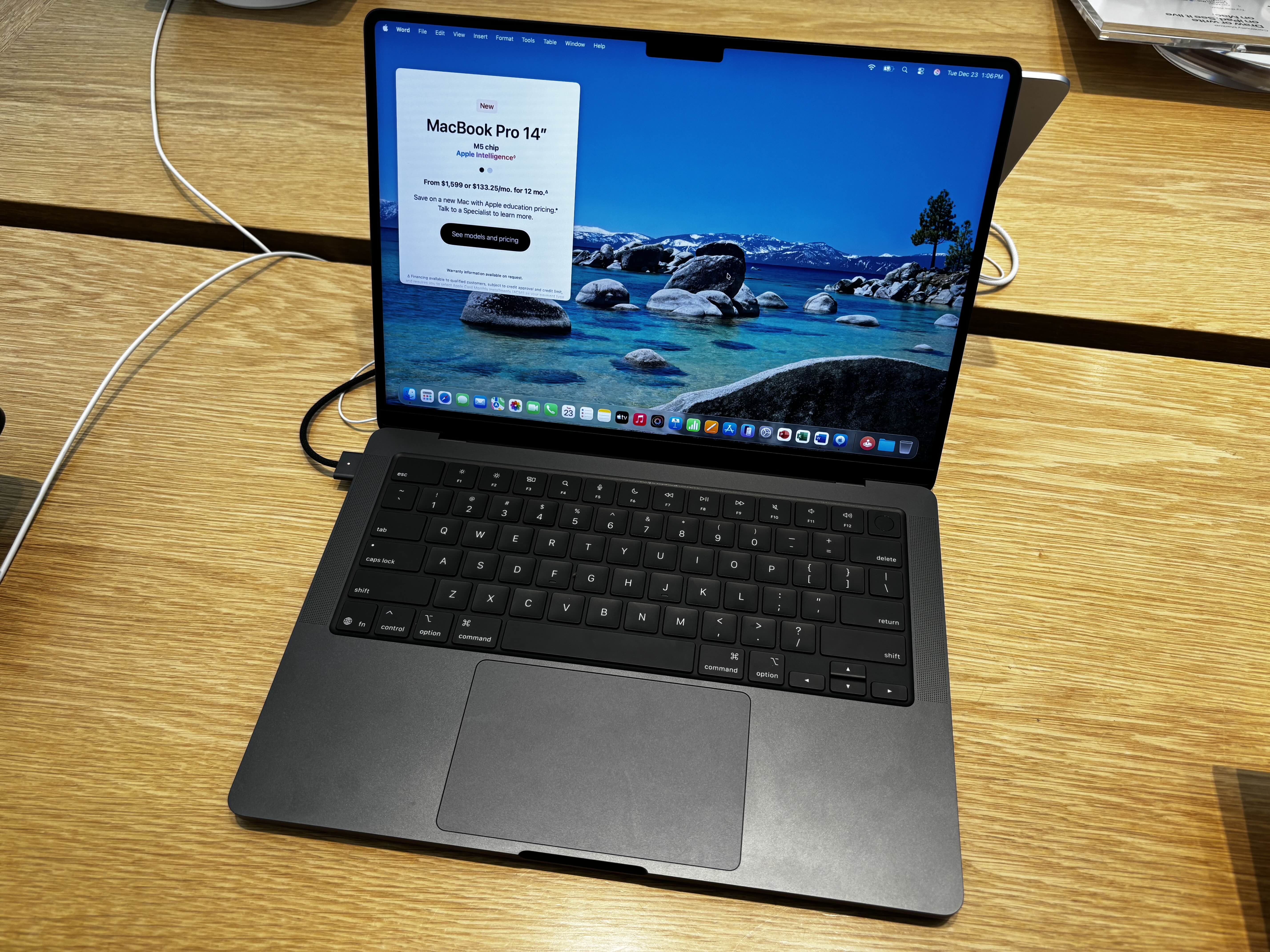 MacBook Pro 14 pouces M5 noir sidéral ouvert sur une table en bois, photo d’archive de décembre 2025 illustrant la génération précédente.