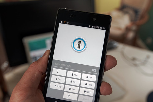 Une main tient un Sony Xperia Z1 affichant l’écran de déverrouillage de 1Password, en 2014.