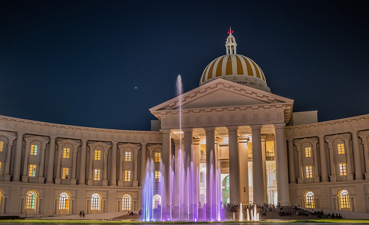Bâtiment GEC 2 éclairé et fontaine du campus Infosys à Mysore, en Inde, photographiés de nuit en 2020.